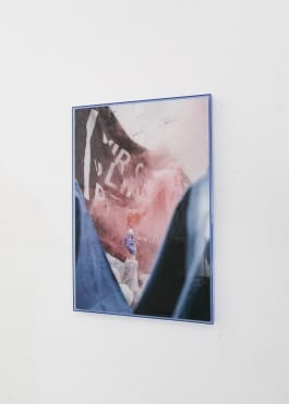 A framed photo showing an extended arm holding up a smoke grenade. The person is covered by a held up banner. 