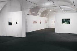 A random length wire antenna segments an exhibition space with various photographs 