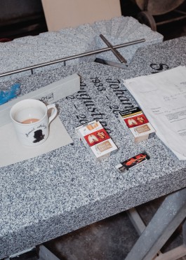 Coffee and Cigarettes on top a grave stone in a stone masons workshop