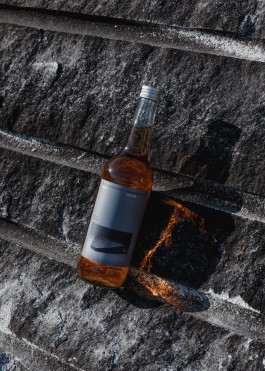 a bottle of fernet propped up against granite charred by blasting