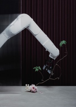 An industrial robotic arm engaged in the practise of ikebana, a japanese traditional flower arrangement.