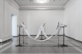 3 Printers on Speaker Stands arranged in a Triangle in a white cube setting. There's a paper band fed through all three of them.